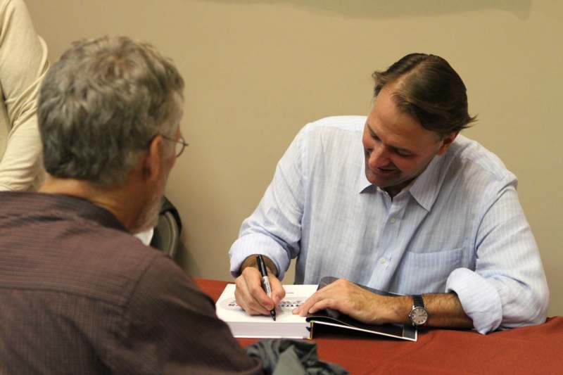 a man signing a book with another man