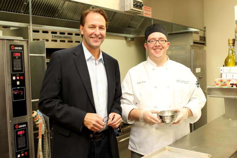 a man in a suit and chef in a kitchen