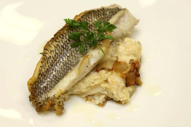 a fish with a garnish on top of a white plate