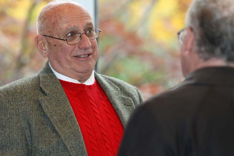 a man in a red sweater and a jacket talking to another man
