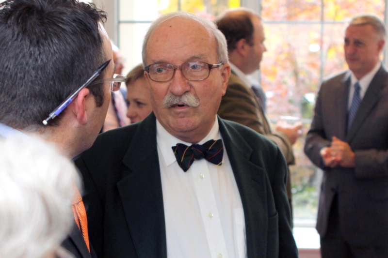 a man in a suit and bow tie talking to another man