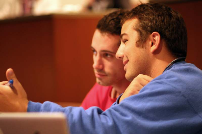 a couple of young men looking at a laptop