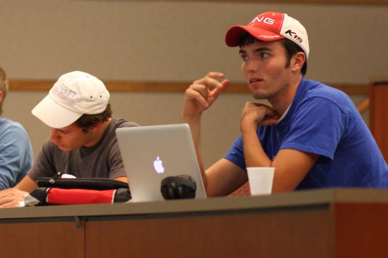 a man in a red hat sitting in front of a laptop