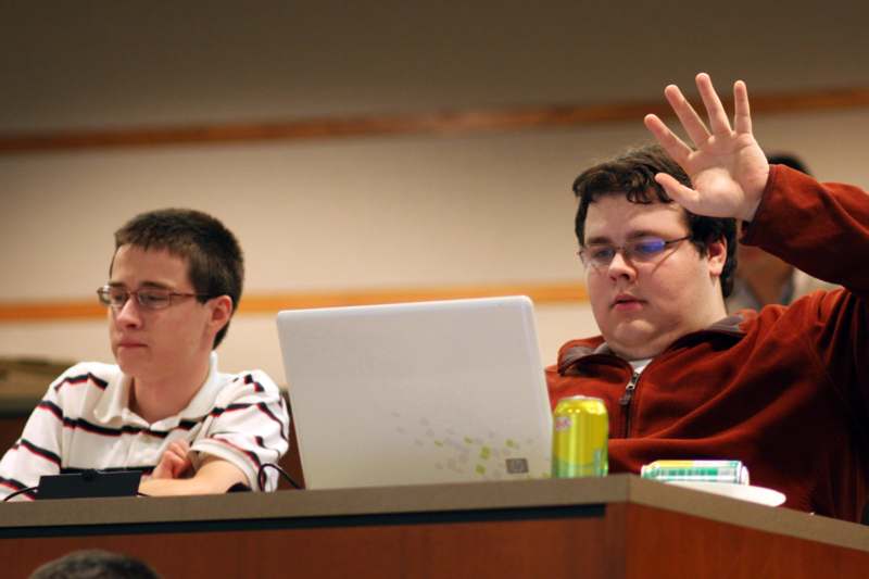 a group of young men sitting at a desk with a laptop