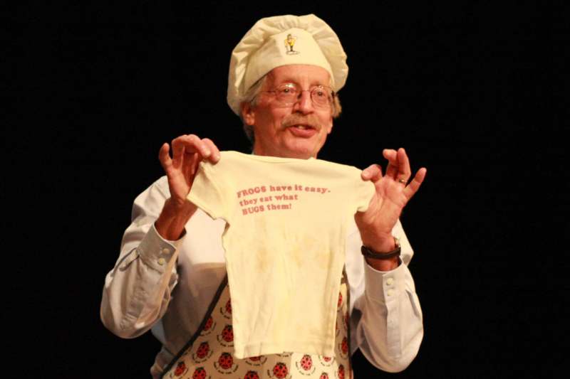 a man wearing a chef hat and apron holding a baby shirt