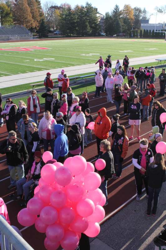 a group of people on a track with pink balloons