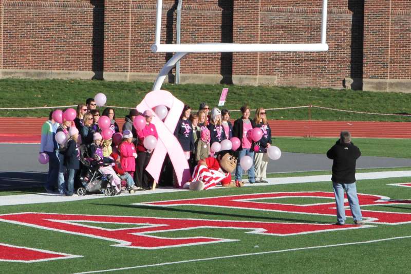 a man standing on a football field with a pink ribbon and a crowd of people