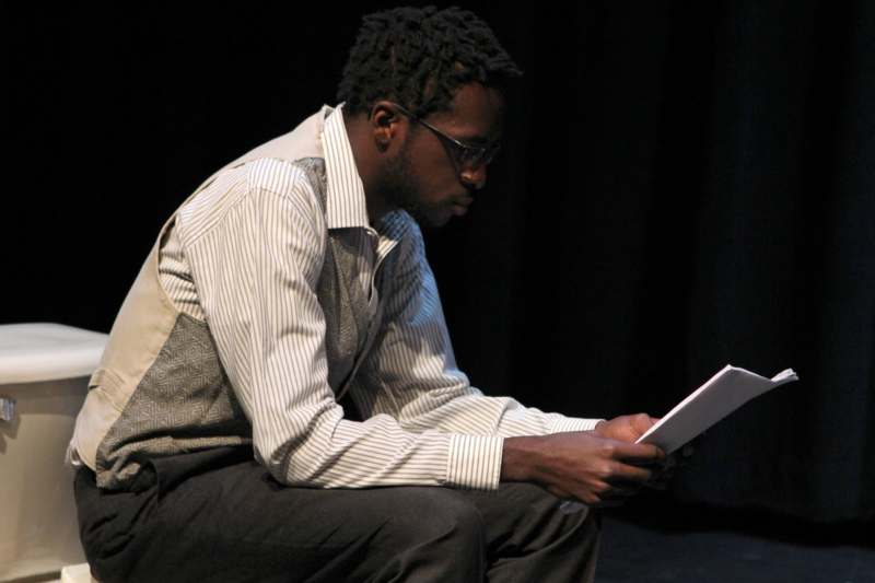 a man sitting on a stage reading a book