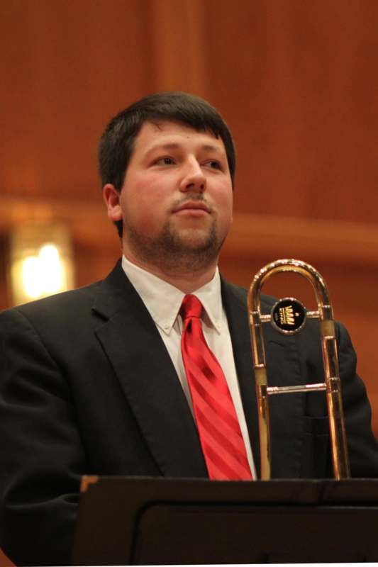 a man in a suit and tie holding a trombone