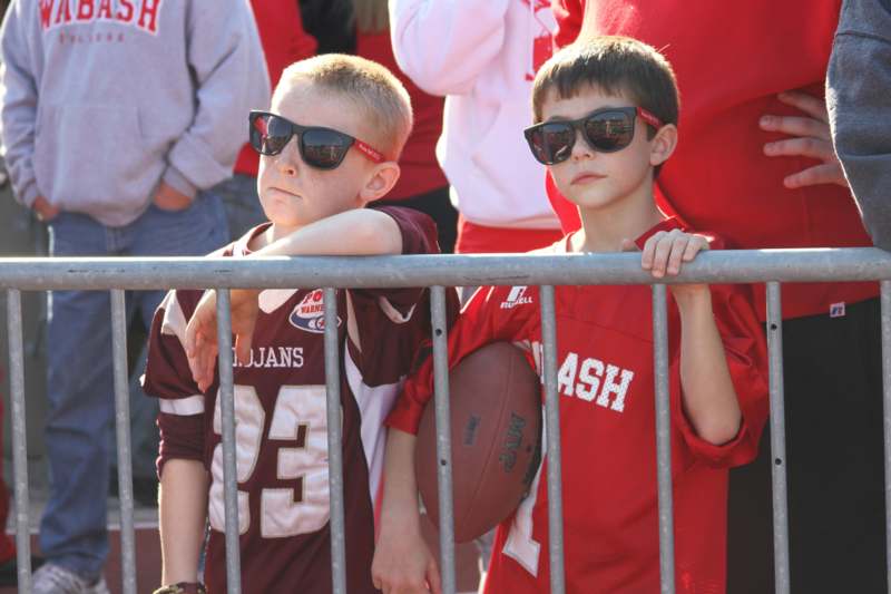 two boys wearing sunglasses and standing next to a fence