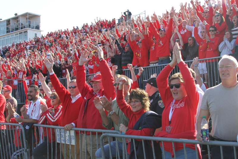 a crowd of people in red shirts raising their hands