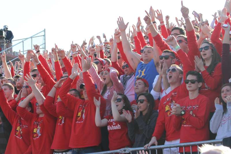 a large crowd of people in red shirts raising their hands