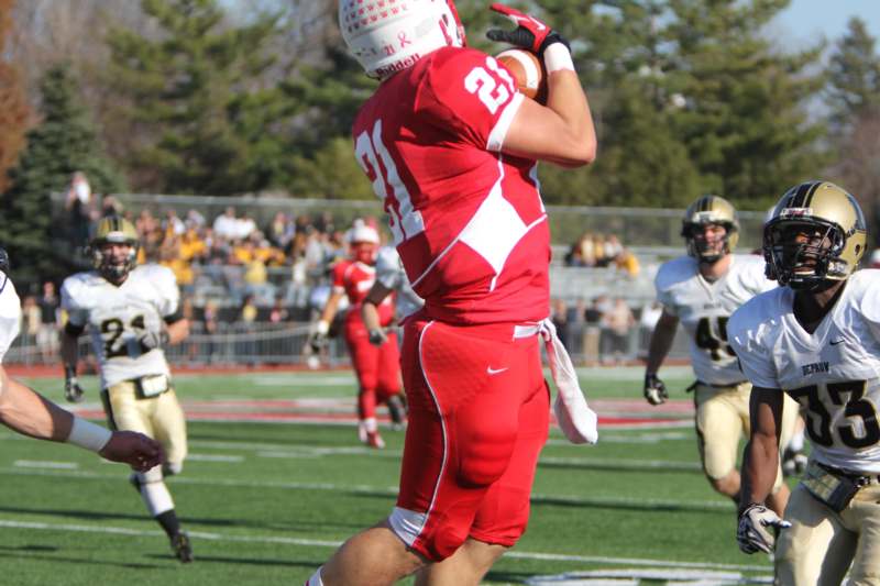 a football player in red uniform running with a football in the air