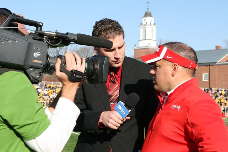 a man in a red shirt and a red visor with a microphone