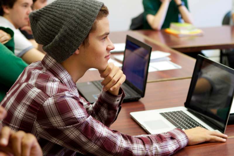 a man in a beanie looking at a laptop
