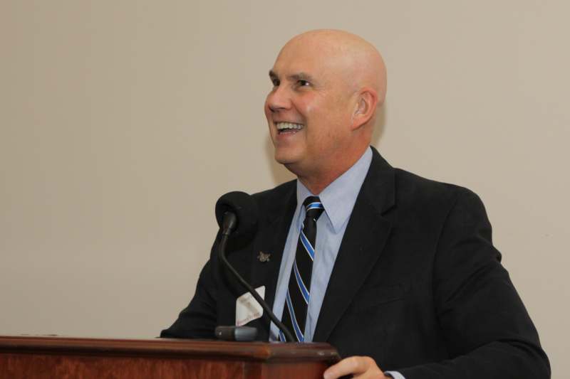 a man in a suit and tie smiling at a podium