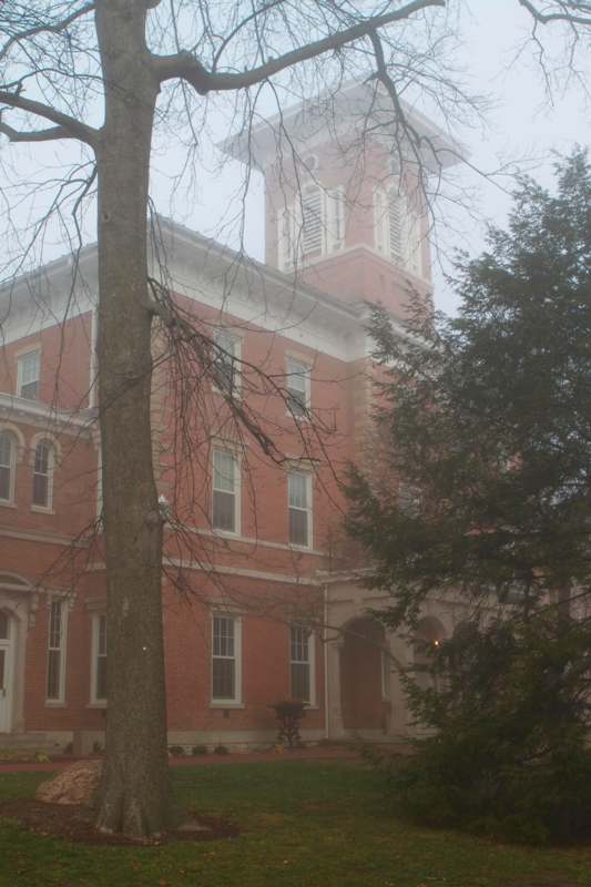 a building with a tower and trees in the fog