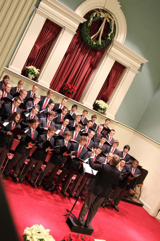 a choir of men singing in front of a large group of people