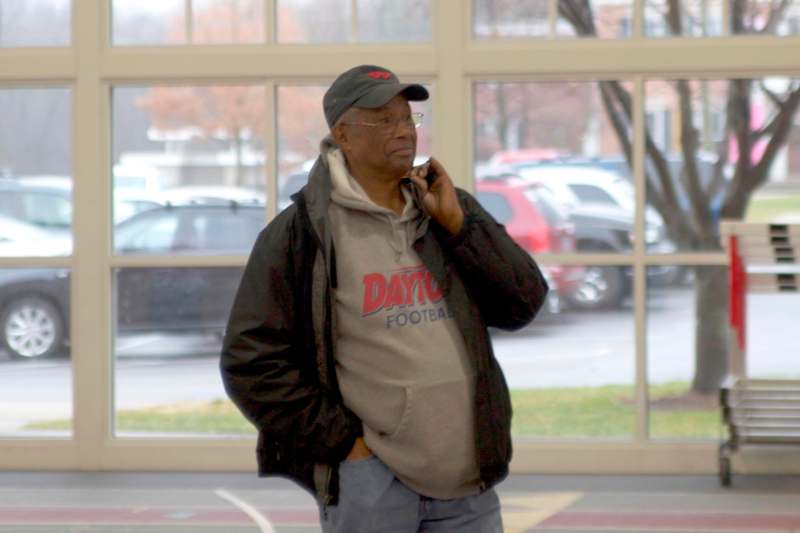 a man in a black jacket and hat talking on a cell phone