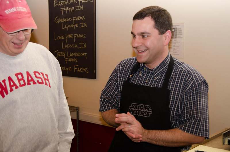a man in an apron talking to another man