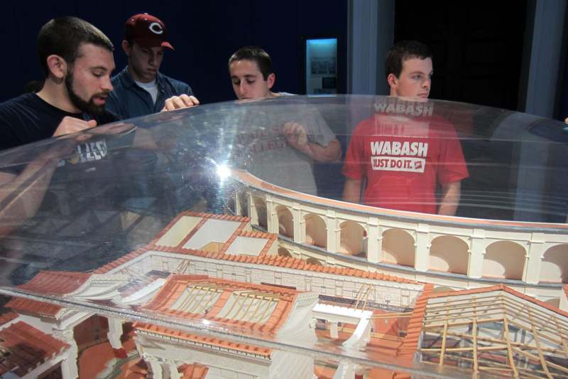 a group of men looking at a model of a building
