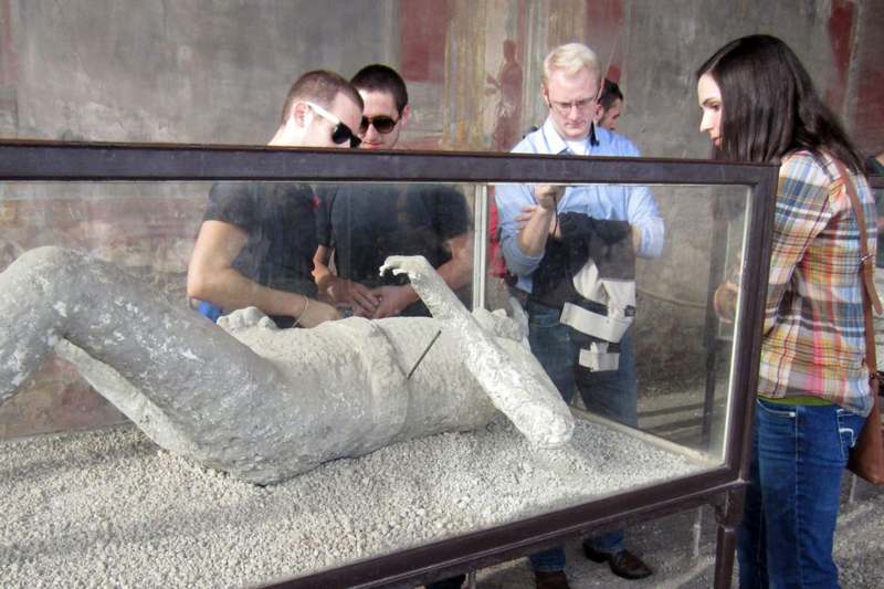 a group of people looking at a statue in a glass case