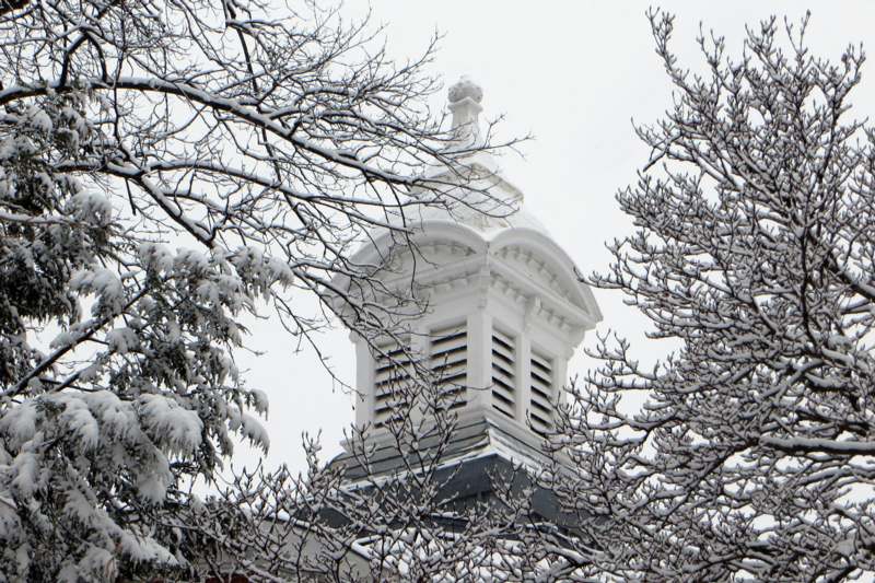 a white building with a steeple and snow covered trees