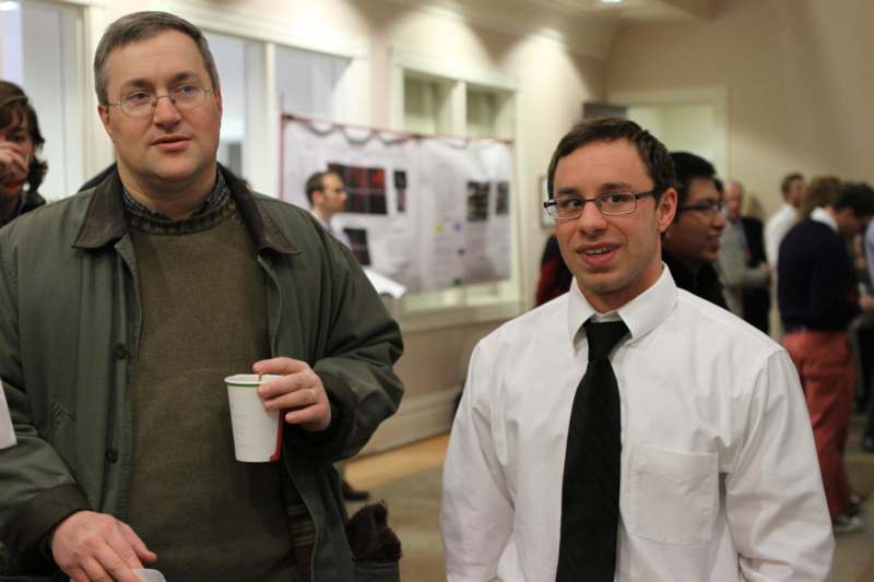 a man holding a cup and standing next to another man
