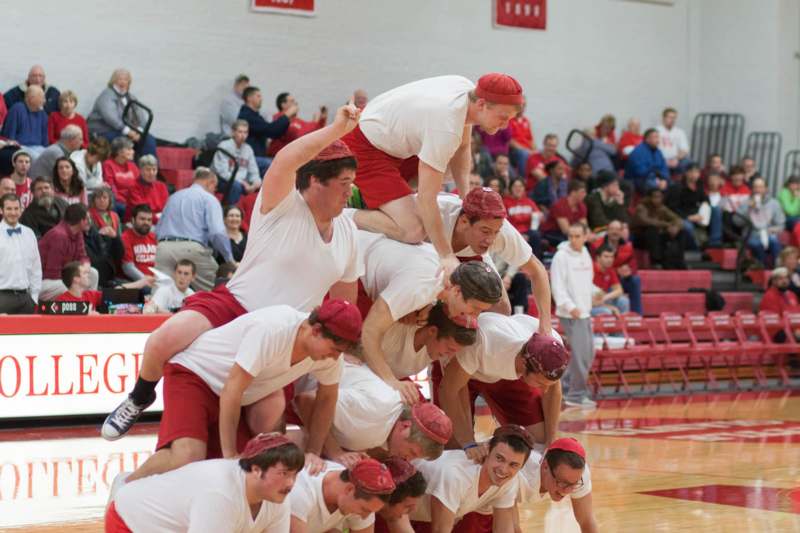 a group of men in white shirts and red hats on each other