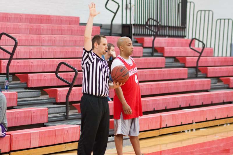 a man holding a basketball and a referee standing in a gym