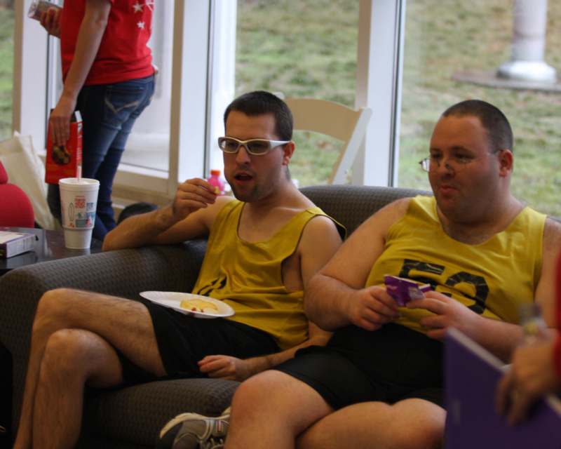 two men sitting on a couch eating food