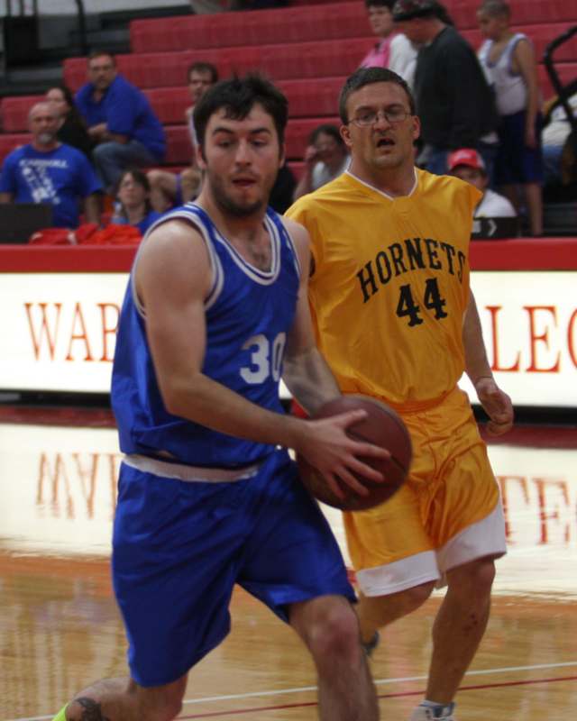 a man in a blue uniform running with a basketball in front of another man