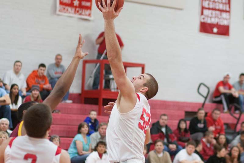 a man in a white jersey jumping to shoot a basketball