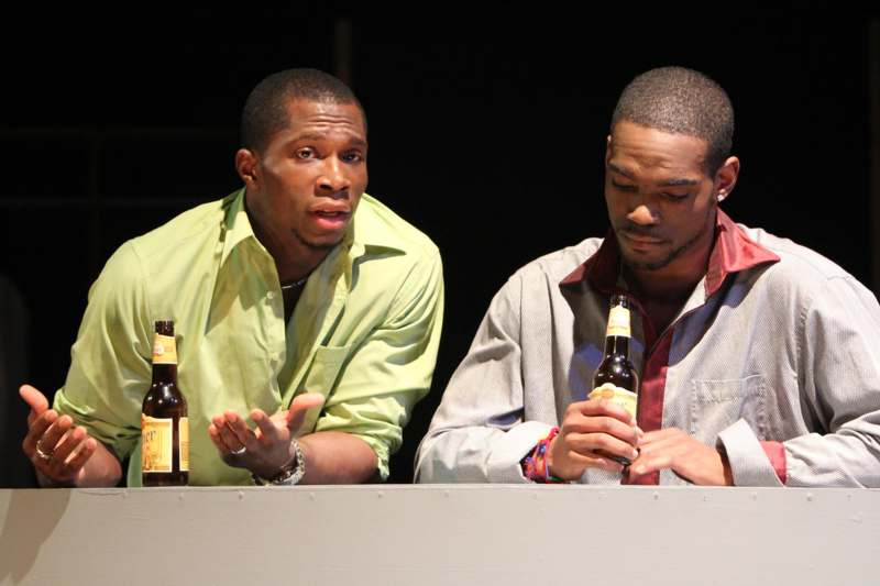 a couple of men sitting at a table with bottles