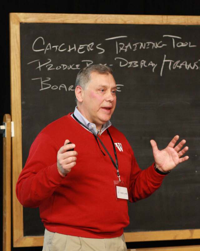 a man in a red sweater standing in front of a chalkboard