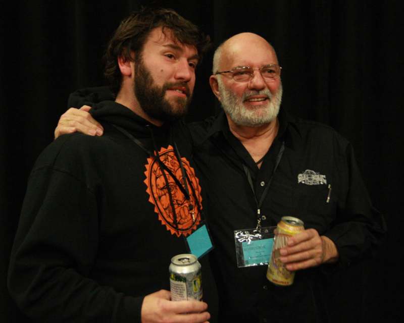 two men holding cans and smiling
