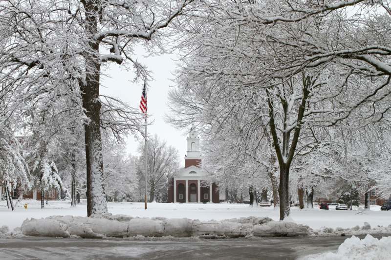 a snowy park with a building and a flag