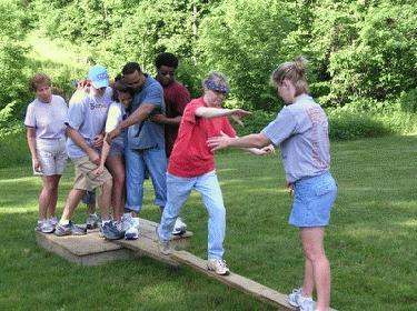 a group of people balancing on a wooden beam