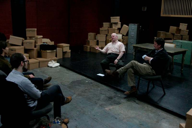 a group of men sitting in chairs in a room with boxes