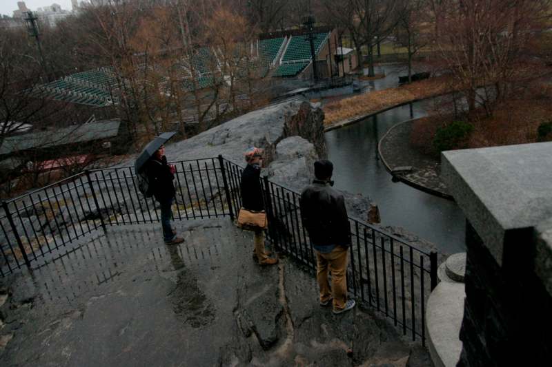 a group of people standing on a ledge looking at a river