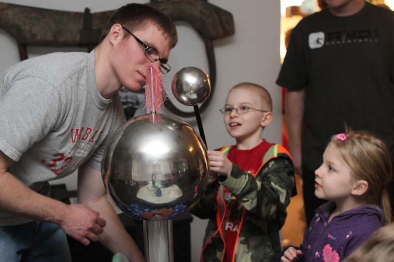 a man and kids looking at a sphere