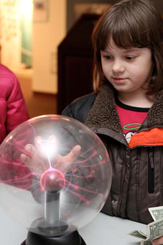 a girl looking at a plasma ball