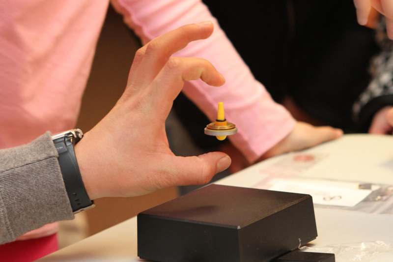 a hand holding a yellow and black spinning top