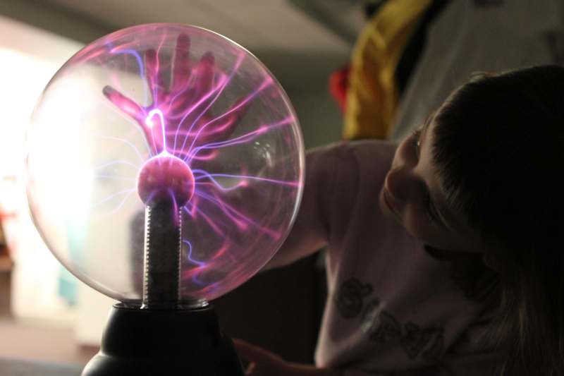 a child looking at a plasma ball