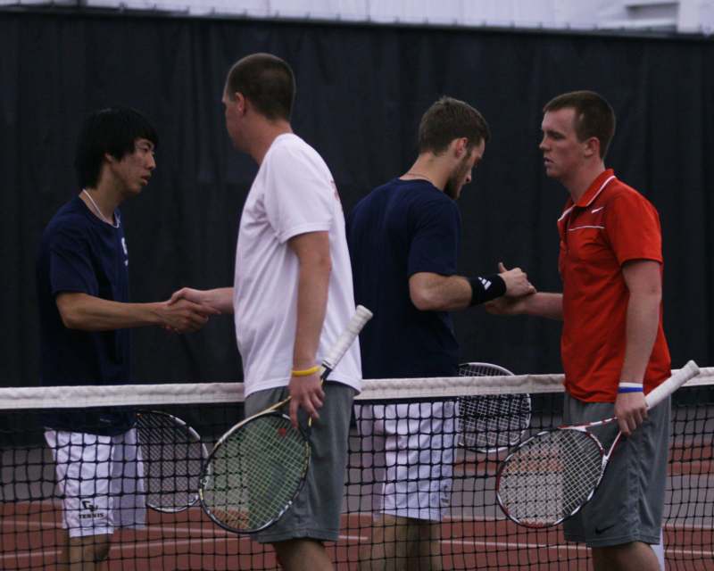 a group of men shaking hands on a tennis court