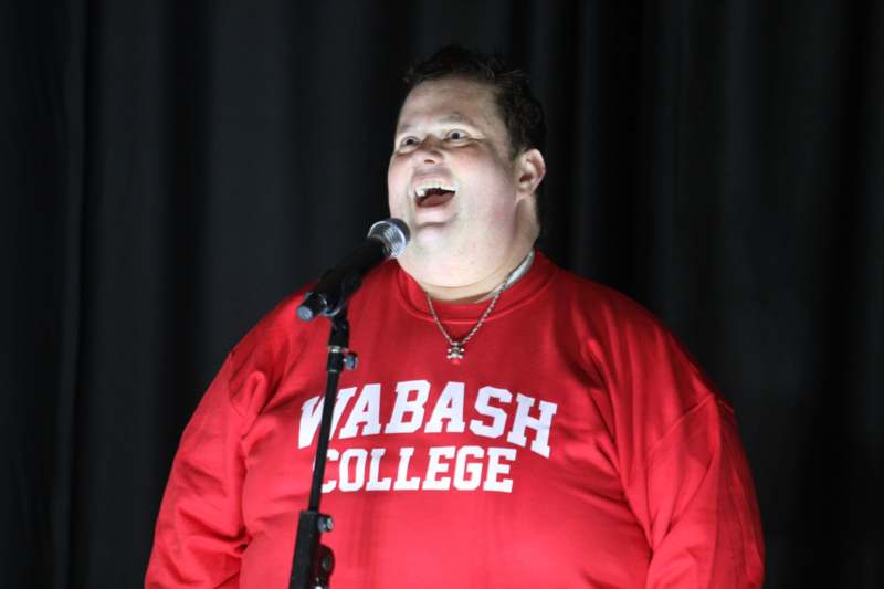 a man in a red shirt singing into a microphone