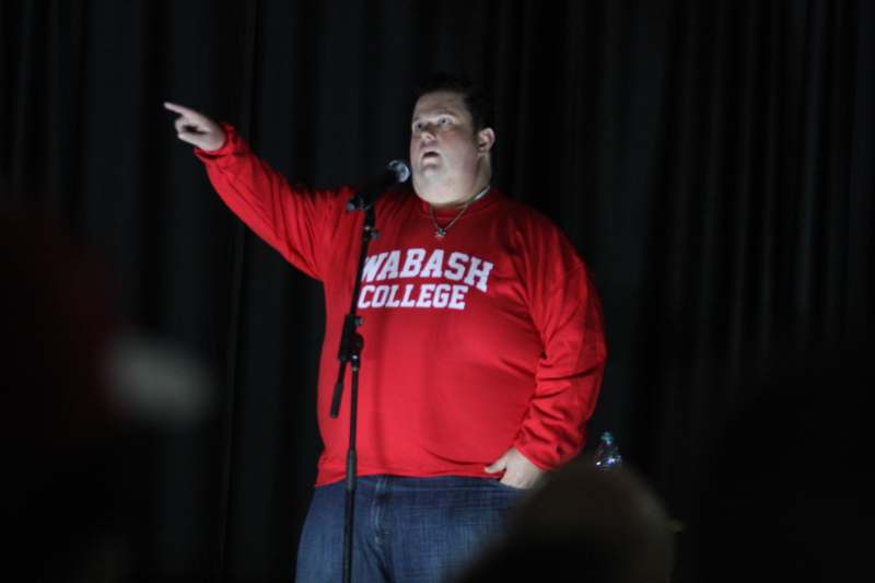 a man in a red shirt pointing at a microphone