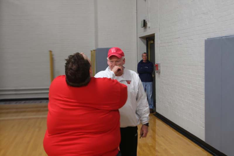 a man in a red hat talking to a man in a gym