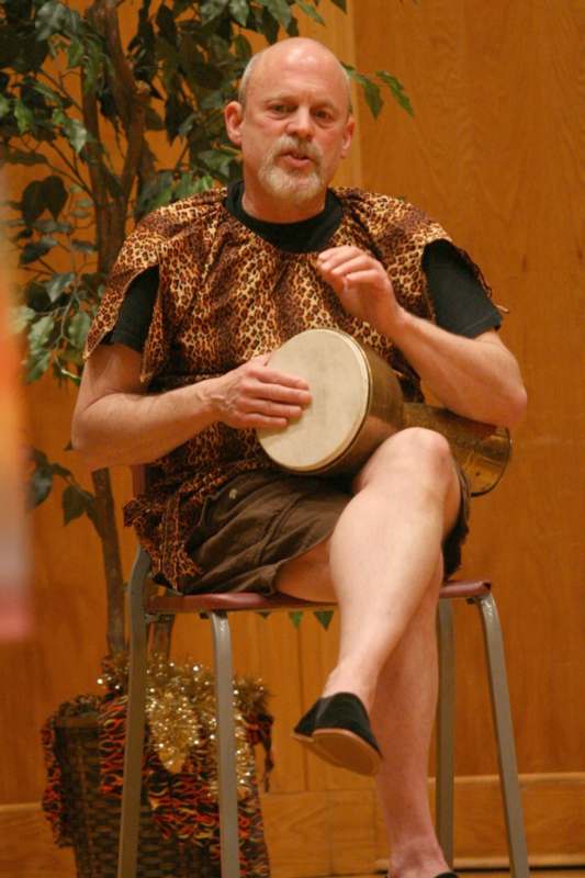 a man in a leopard print garment playing a drum