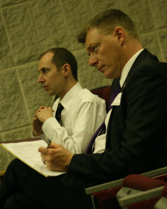 a man in a suit and tie sitting next to another man in a suit and tie